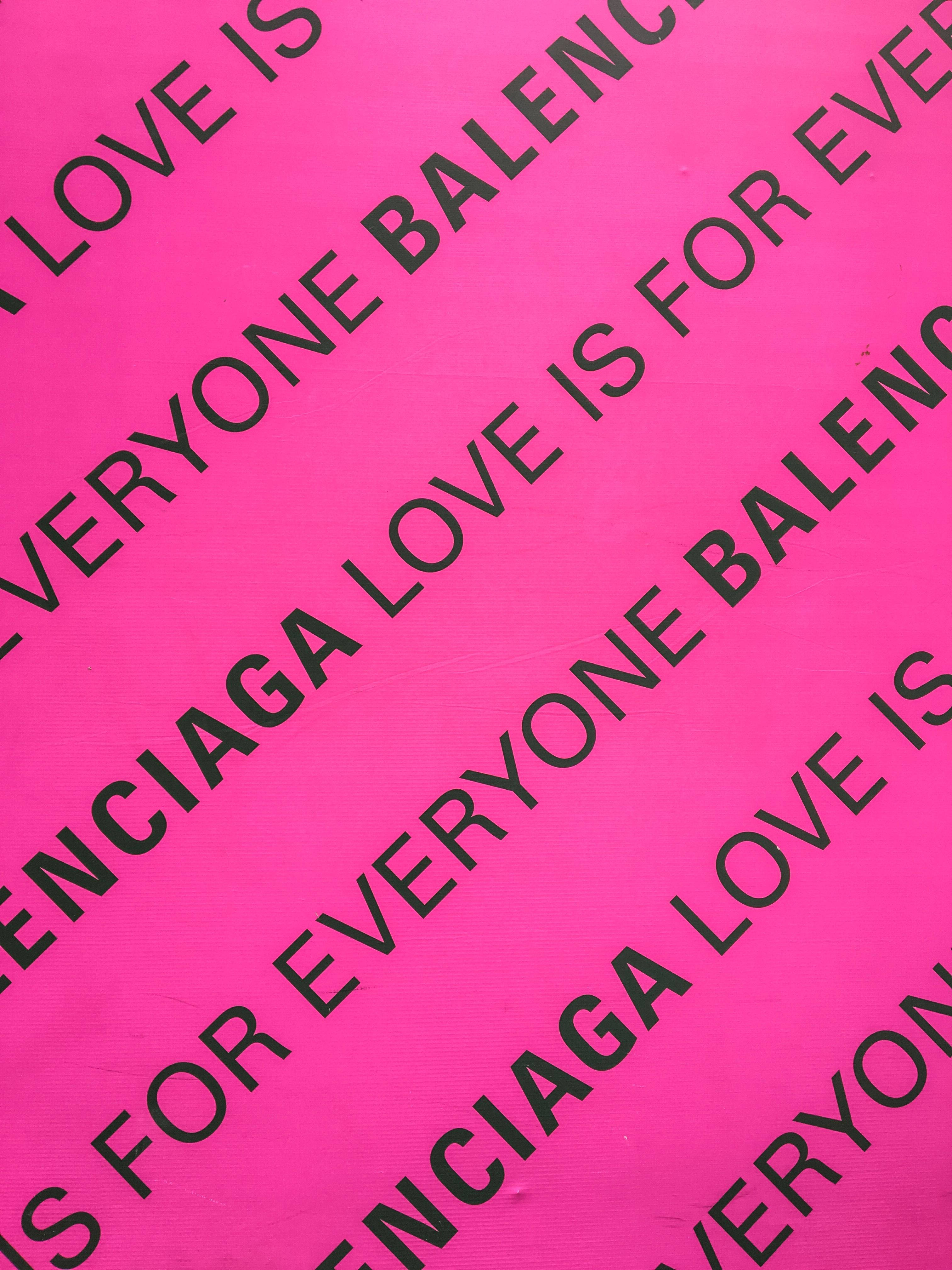 Balenciaga 黑粉配色 壁紙 — 充滿活力的粉紅色牆紙，帶有重複的黑色文字，以對角線條紋顯示「LOVE IS FOR EVERYONE BALENCIAGA」。