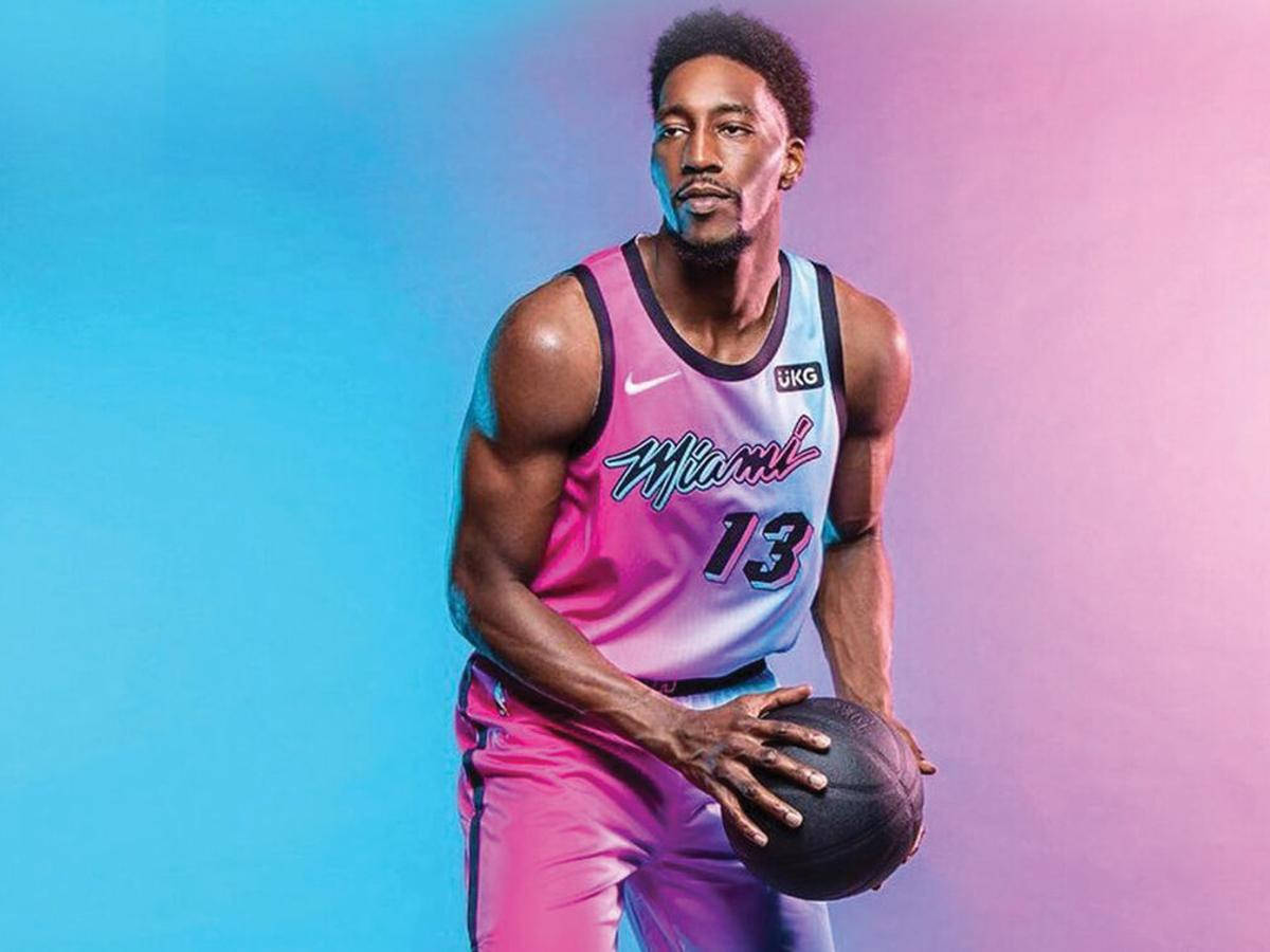 Bam Adebayo 對比藍粉背景 壁紙 — 一名身穿鮮豔粉紅和藍色邁阿密球衣的籃球運動員，在漸變藍色和粉紅色的攝影棚背景前持球。