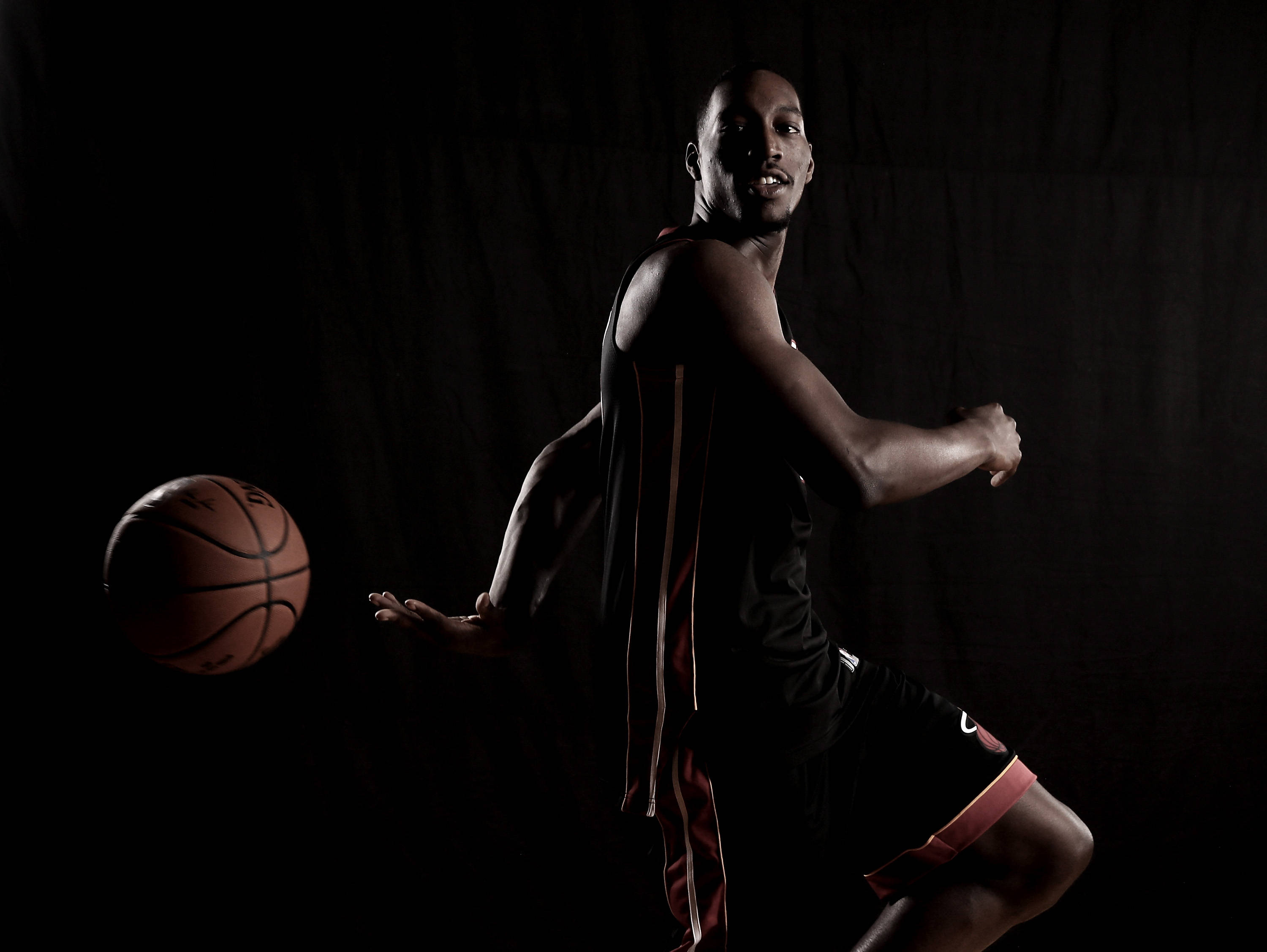 Bam Adebayo 攝影棚拍攝 壁紙 — 一名籃球運動員在黑暗背景下移動，戲劇性的燈光凸顯他的姿勢和球。