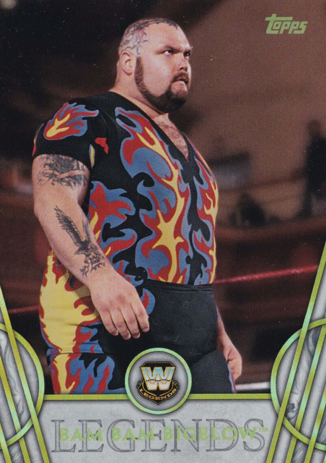 Bam Bam Bigelow 2018 Legends WWE (Topps) 卡片壁紙 壁紙 — Bam Bam Bigelow 站在摔角擂台上，身穿帶有醒目紅、藍、黃火焰圖案的黑色襯衫和黑色短褲。
