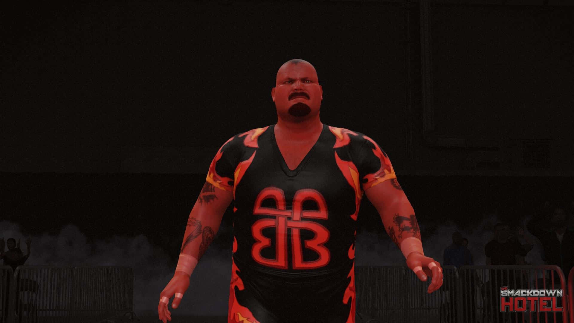 Bam Bam Bigelow WWE 2K17 隊伍登場 壁紙 — 一位肌肉發達的摔角手穿著黑色和橙色火焰圖案襯衫，帶有'BB'標誌，在煙霧和人群背景的昏暗競技場中威風凜凜地站立。