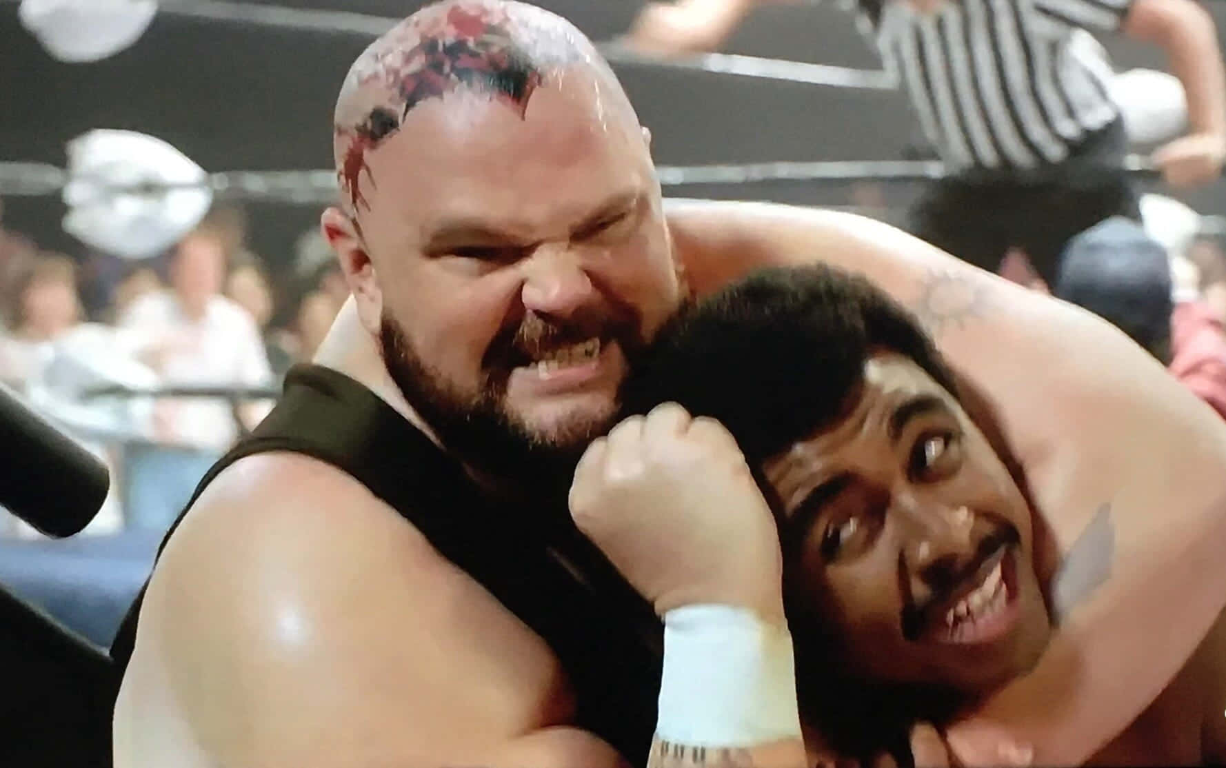 Bam Bam Bigelow 對戰 Rocky Johnson《Young Rock》 壁紙 — 兩名摔角手在擂台上激烈纏鬥，背景有裁判和觀眾。