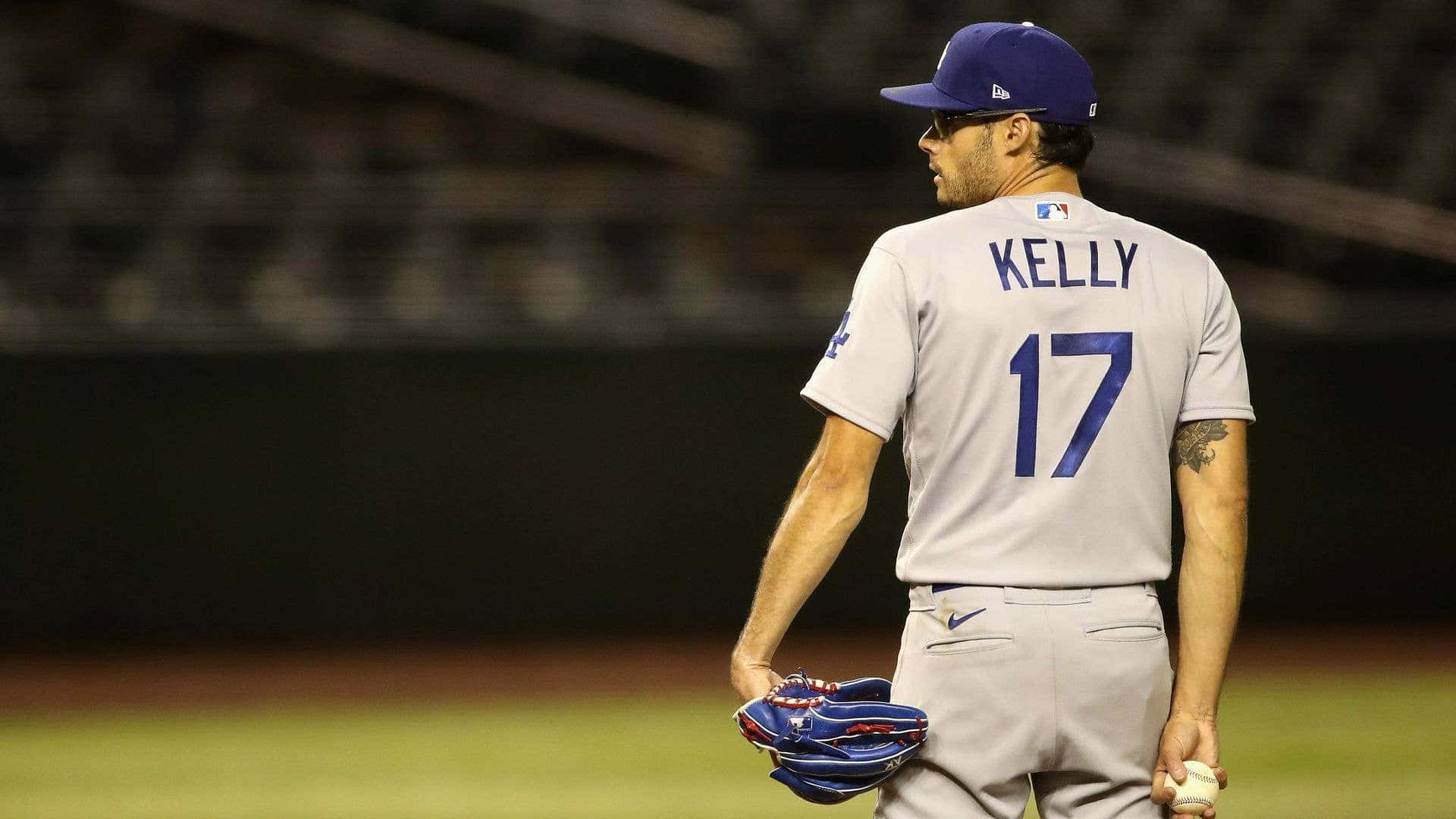  壁紙 — 一名身穿灰色球衣、藍色17號及名字KELLY的棒球選手在夜間球場上背對鏡頭走開。