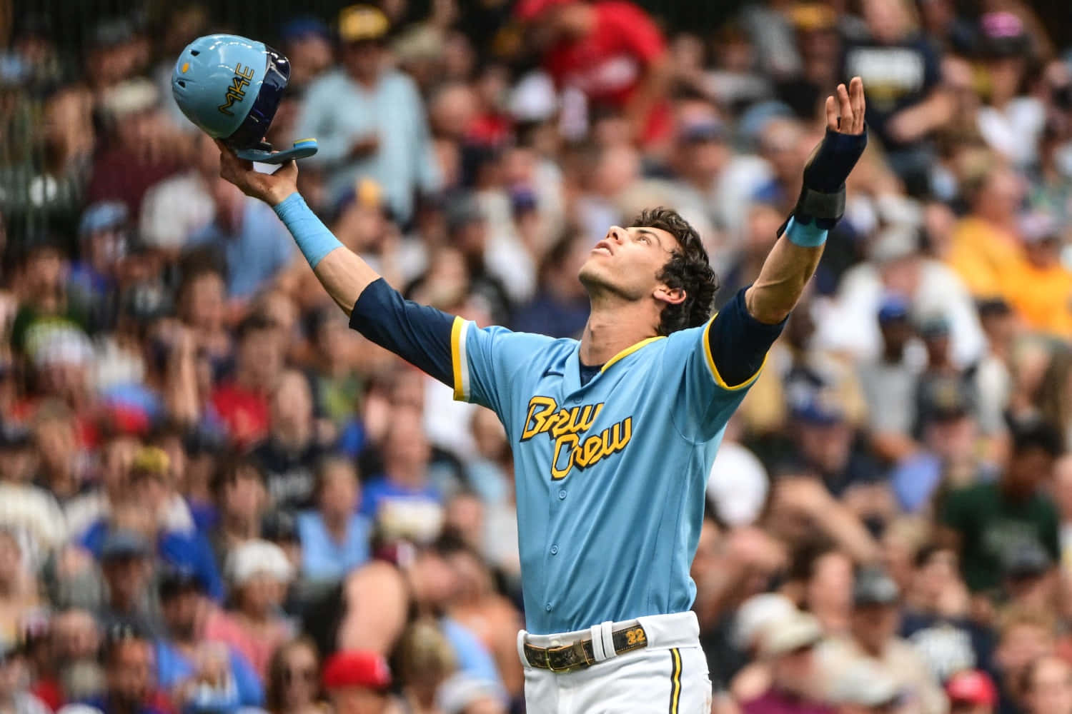  壁紙 — 一名身穿淺藍色 'Brew Crew' 球衣的棒球運動員，在歡呼的人群中，勝利地將頭盔和雙臂舉向天空。