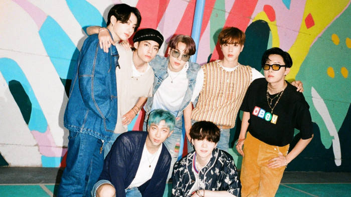 Bangtantv 色彩牆BTS 壁紙 — 七位時尚年輕男子在充滿活力的塗鴉牆前自信擺姿勢，牆上有大膽的抽象圖案。