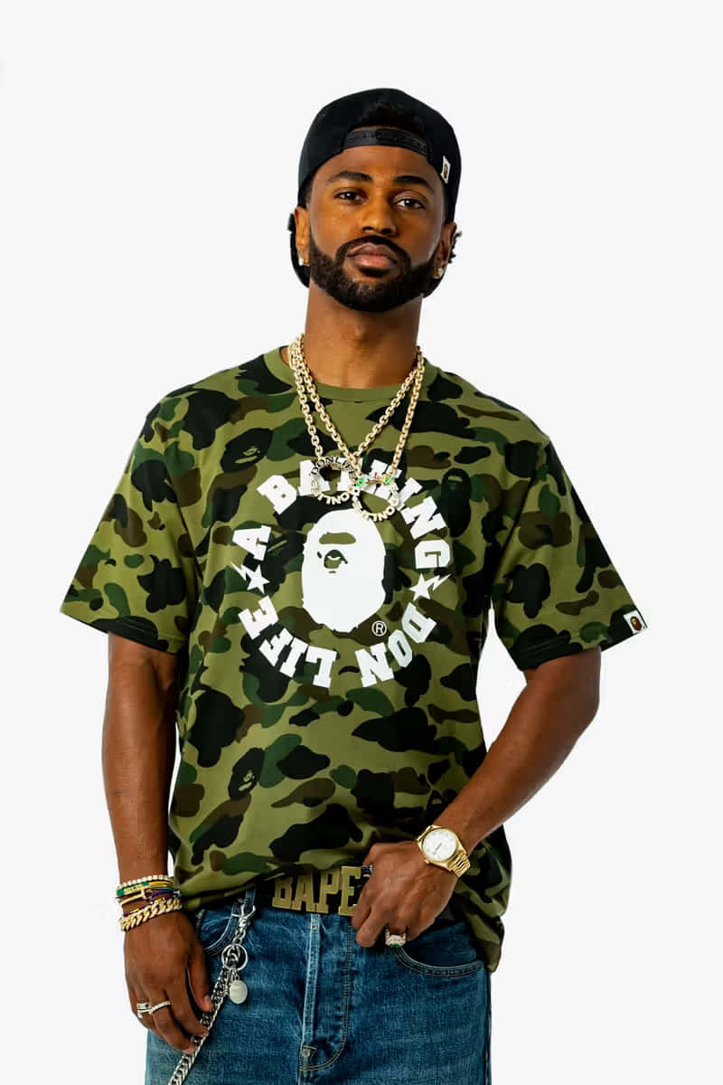 以BAPE提升你的街頭風格！ 壁紙 — 一位時尚男士身穿迷彩Bape T恤和金色鏈條，在純白背景前自信擺姿勢。