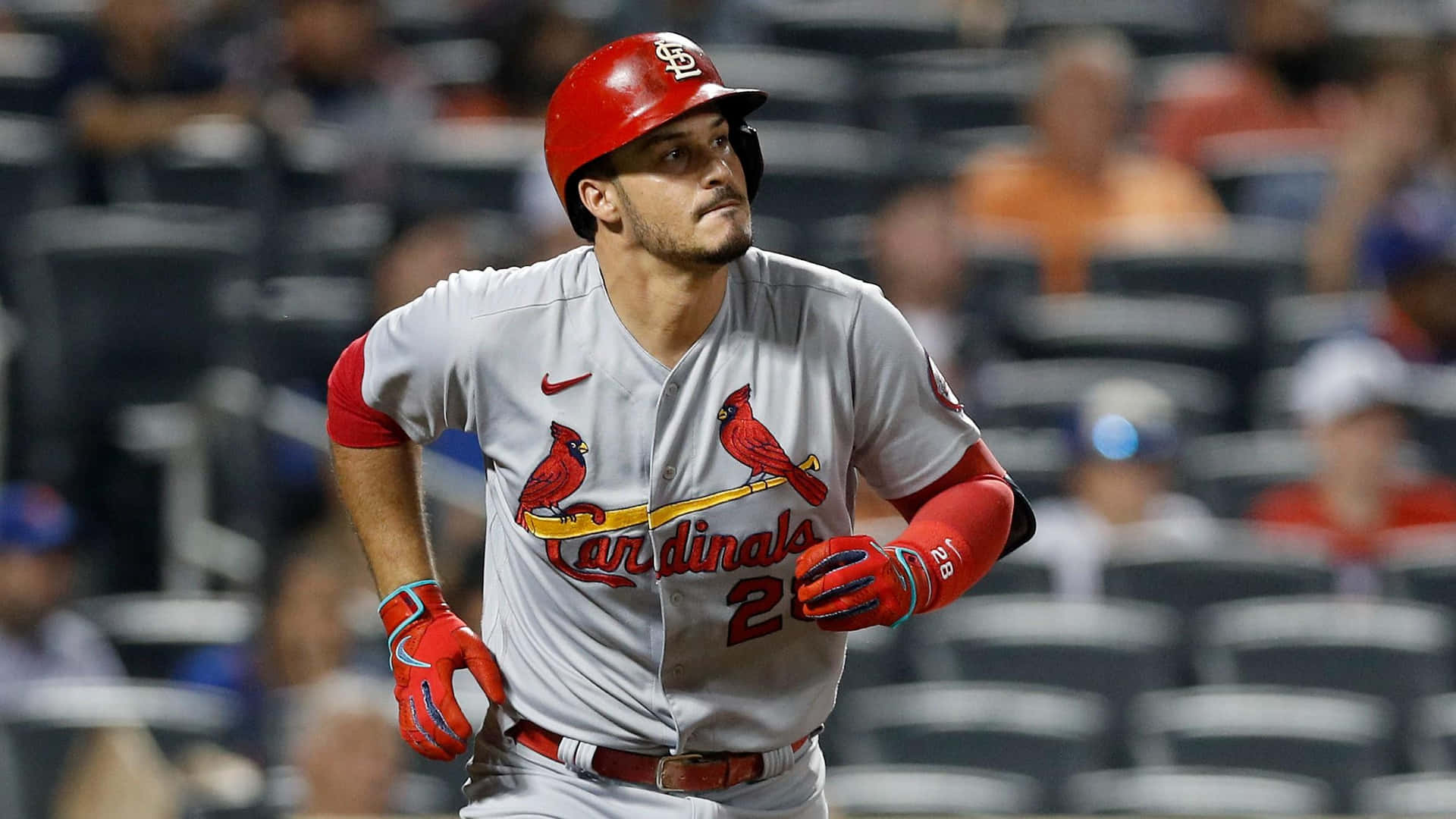  壁紙 — 身穿紅灰色 Cardinals 球衣的棒球運動員在球場燈光下奔跑，背景是模糊的人群。