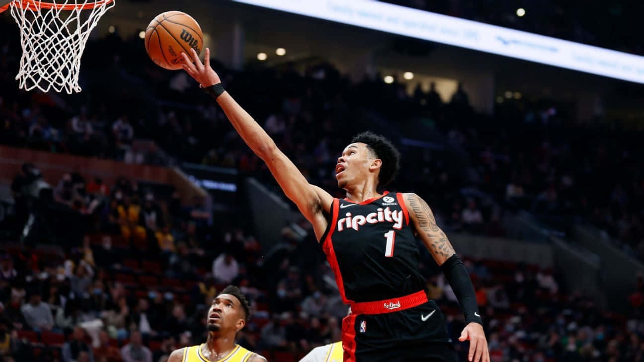  壁紙 — 一名身穿黑色 Rip City 球衣的籃球運動員在明亮的場館燈光下，於比賽中專注地灌籃。
