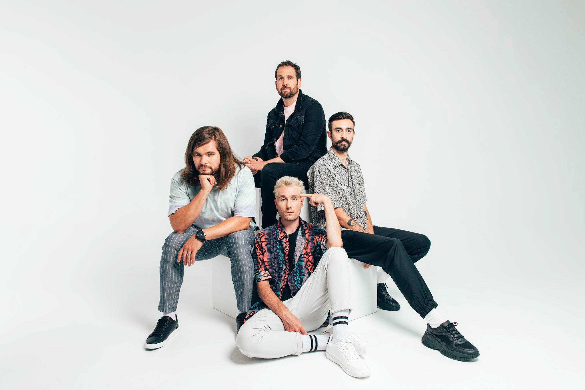 Bastille 照片棚拍 壁紙 — 四位時尚男士自信地站在白色方塊上，背景是無縫的白色攝影棚。