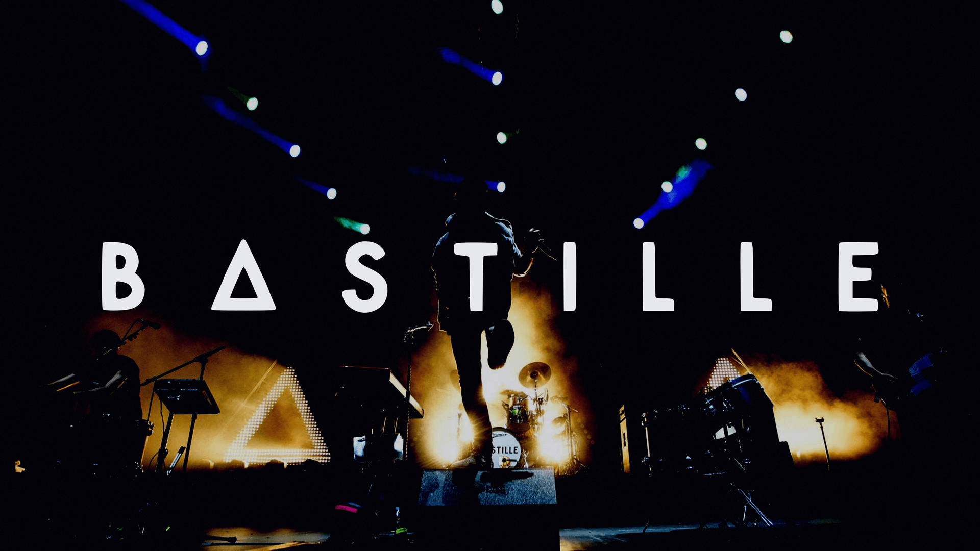 Bastille樂隊舞台 壁紙 — 一位剪影音樂家在黑暗的舞台上表演，舞台被火橙色和電光藍色燈光籠罩，樂隊名稱 Bastille 以粗體白色字母呈現。