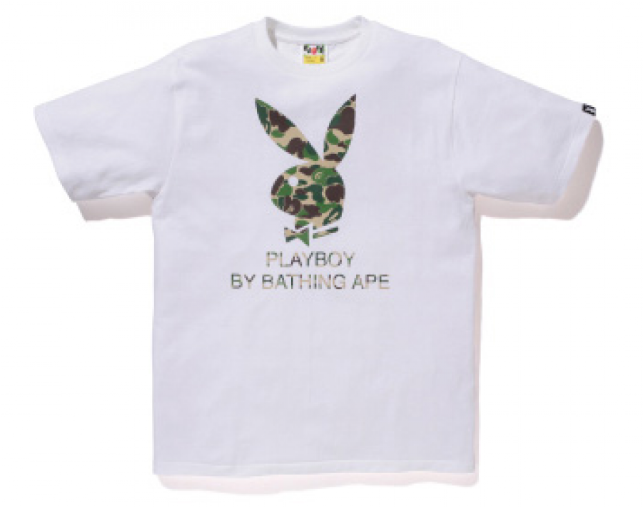 花花公子與BATHING APE聯名T恤 壁紙 — 白色T恤，帶有迷彩Playboy兔子標誌和文字「PLAYBOY BY BATHING APE」，背景純色。