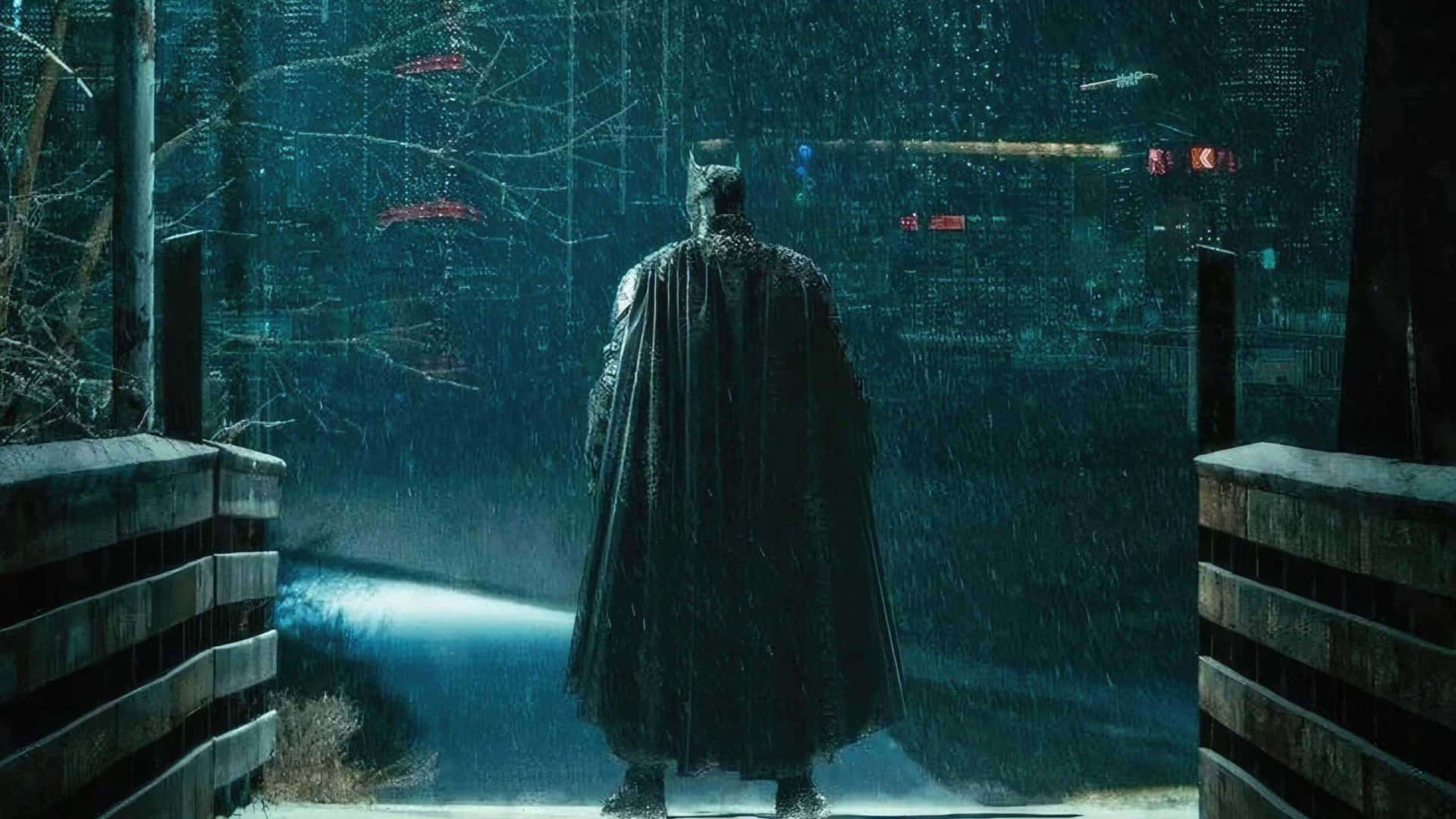  壁紙 — 蝙蝠俠獨自站在夜間被雨水浸透的城市小巷中，他的斗篷隨風飄揚，城市燈光透過傾盆大雨閃爍。