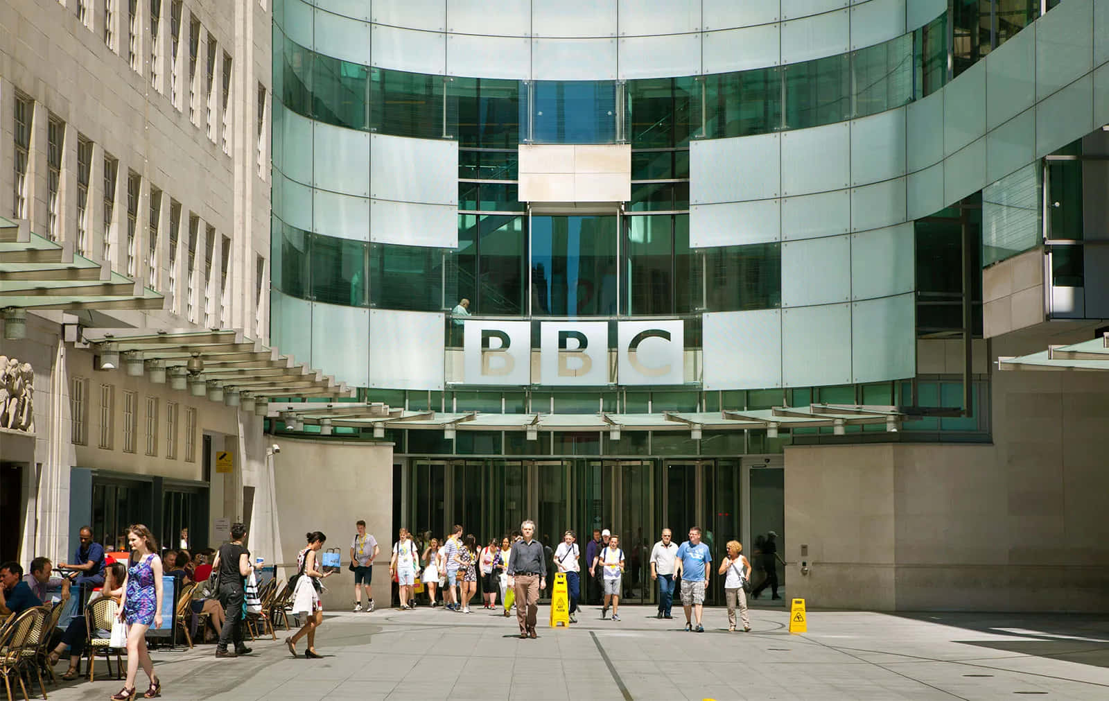 BBC建築入口，人們在陽光明媚的日子裡在外面走動和坐著。