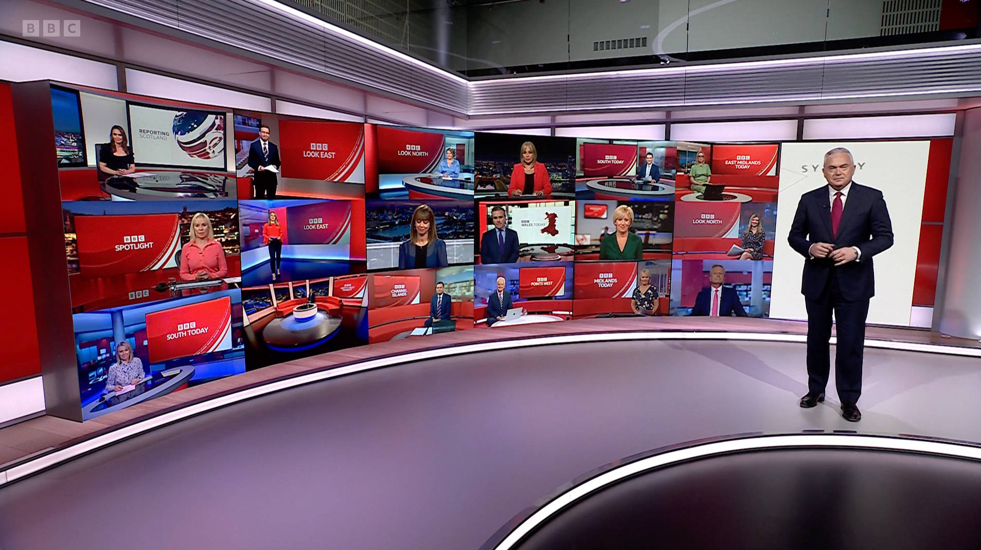 BBC新聞主播在多個視頻屏幕的高科技錄影廠中進行播報。