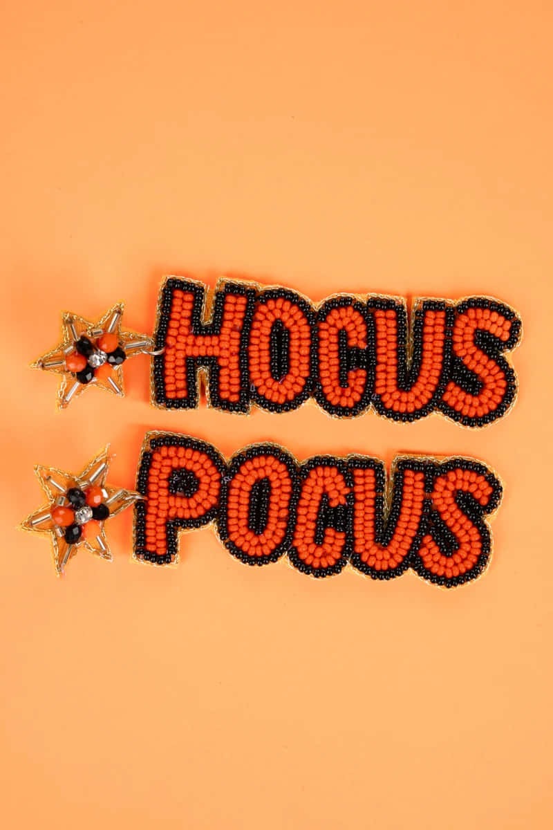  壁紙 — 在桃色背景上，以橙色、黑色和金色珠子串成的「HOCUS POCUS」文字和星星耳環。