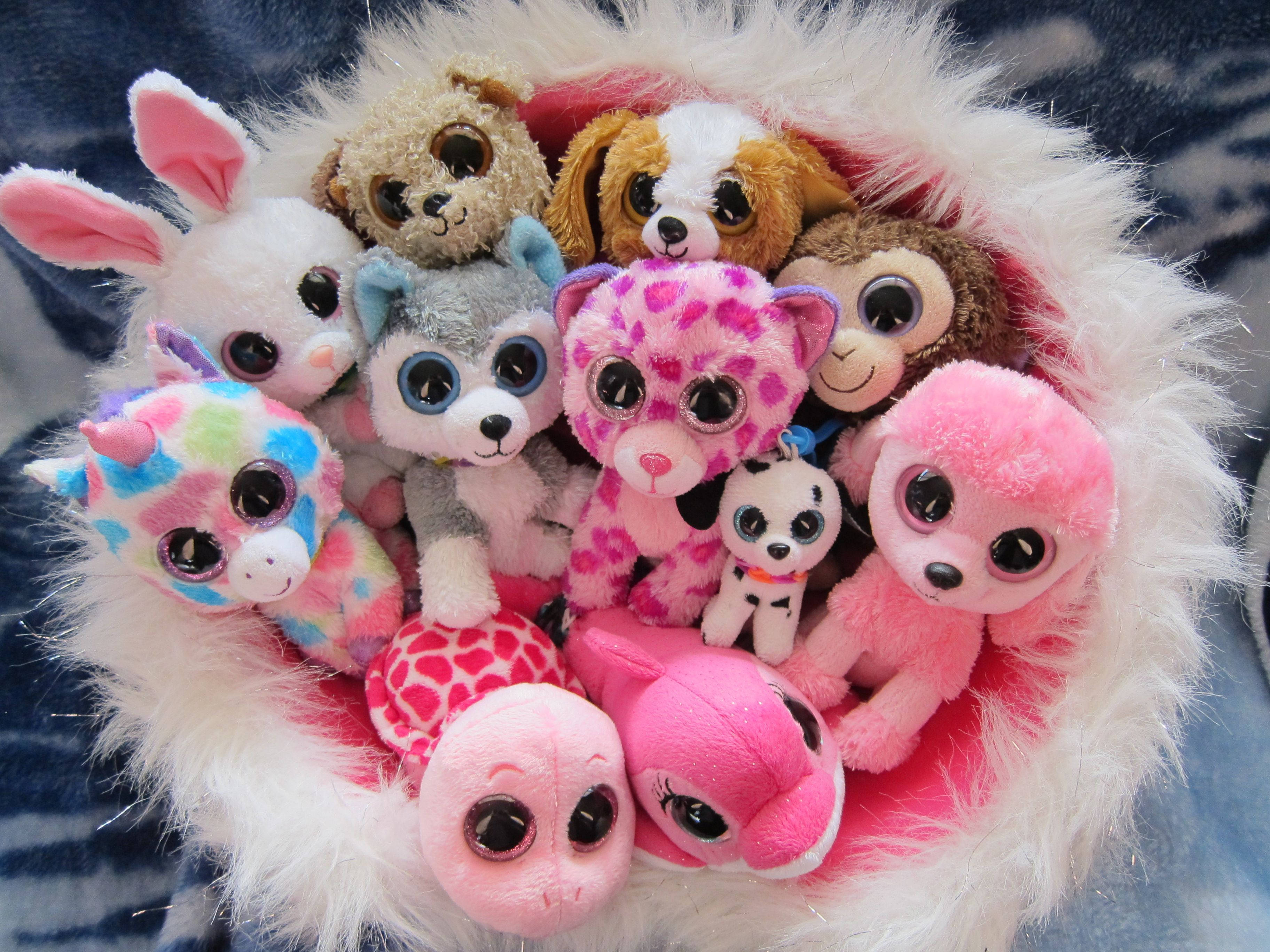 Beanie Boos 在巢穴中 壁紙 — 一堆色彩繽紛、大眼睛的毛絨玩具，舒適地窩在一個 fluffy 白色碗裡。