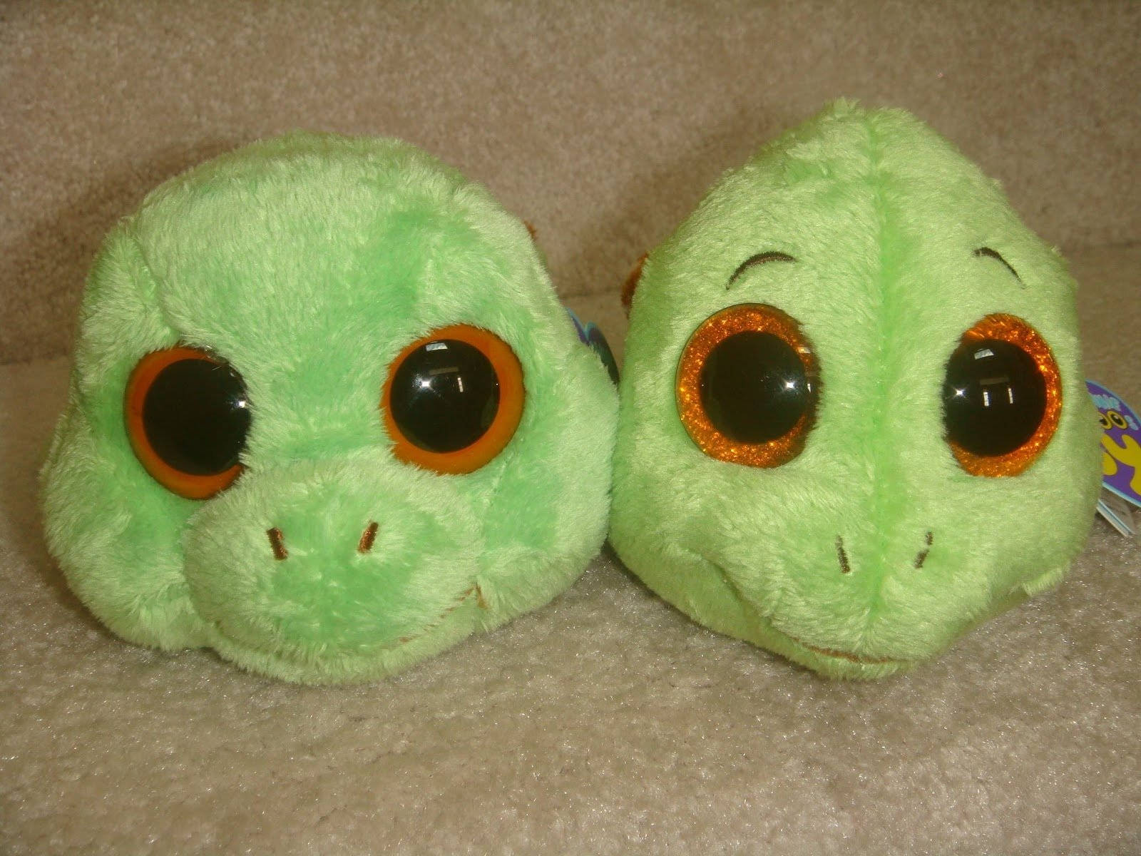 Beanie Boos烏龜頭部 壁紙 — 兩個淺綠色毛絨龜頭，帶有閃閃發光的橙色眼睛，並排坐在米色地毯上。