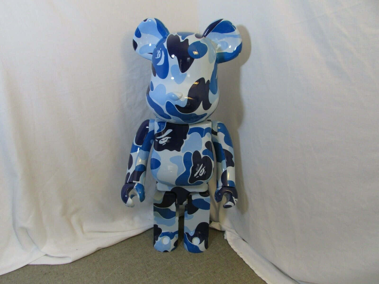亮面藍白迷彩圖案 Bearbrick 玩具，站在白色背景前。
