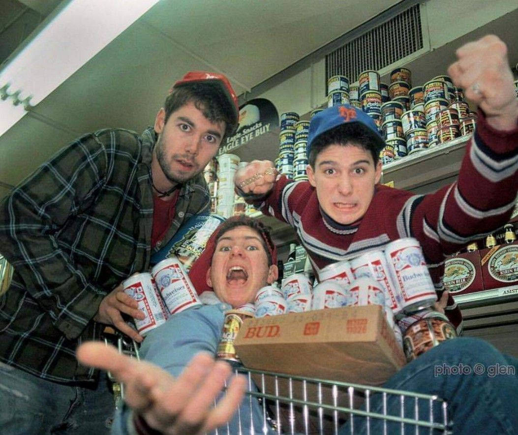 Beastie Boys Budweiser啤酒拍攝推車壁紙 壁紙 — 三名年輕男子在酒舖內拿著啤酒罐和裝滿Budweiser的購物車瘋狂擺姿勢。