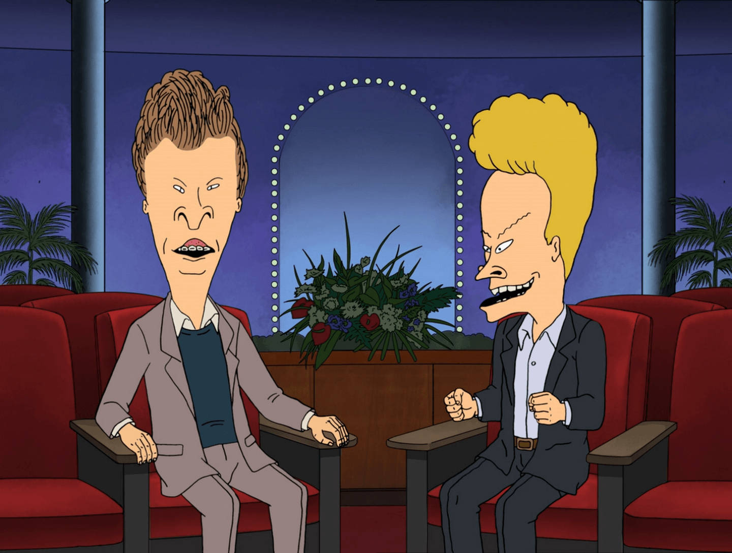 Beavis 和 Butt-Head 談話節目 壁紙 — 兩個誇張特徵的動畫角色坐在紅色椅子上，在昏暗的錄影棚環境中面對面。
