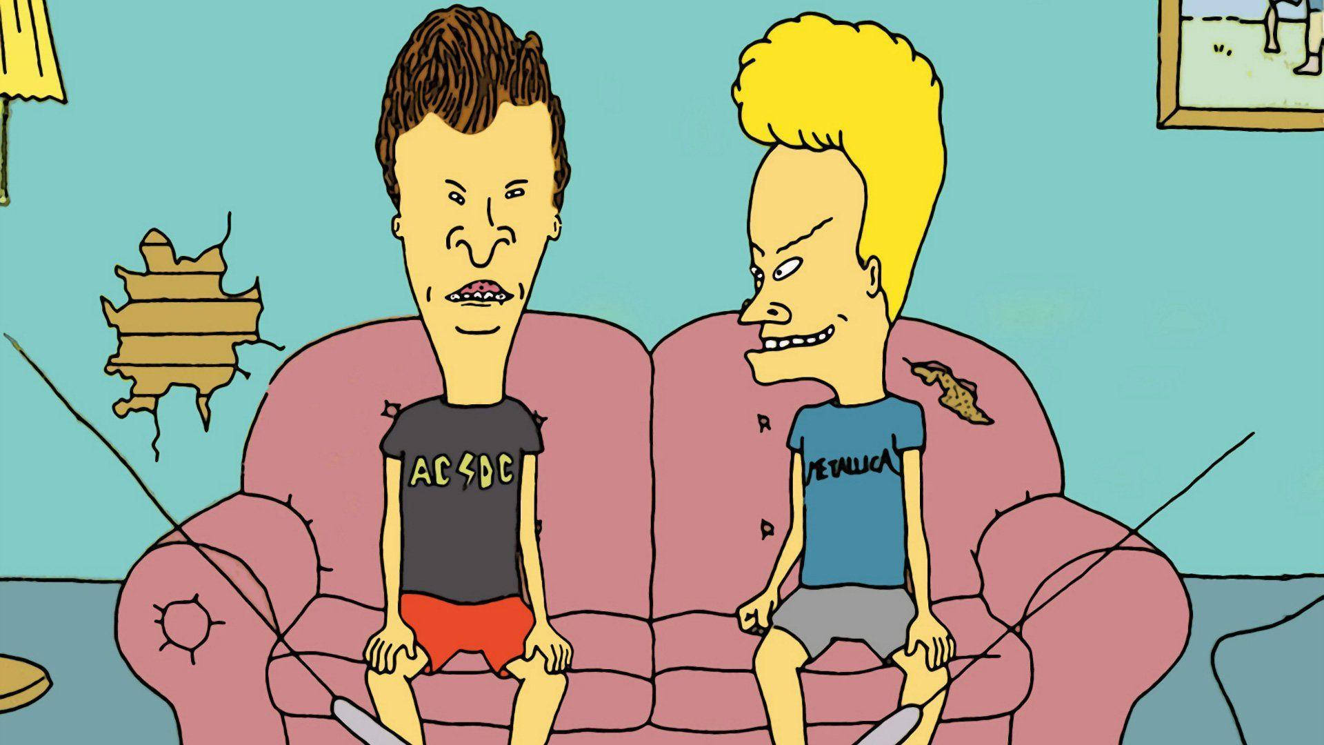 Beavis 和 Butt-Head 坐在粉紅沙發上 壁紙 — 兩個誇張特徵的卡通男人坐在一張破舊的粉紅色沙發上，身處一個牆壁破爛的凌亂客廳。