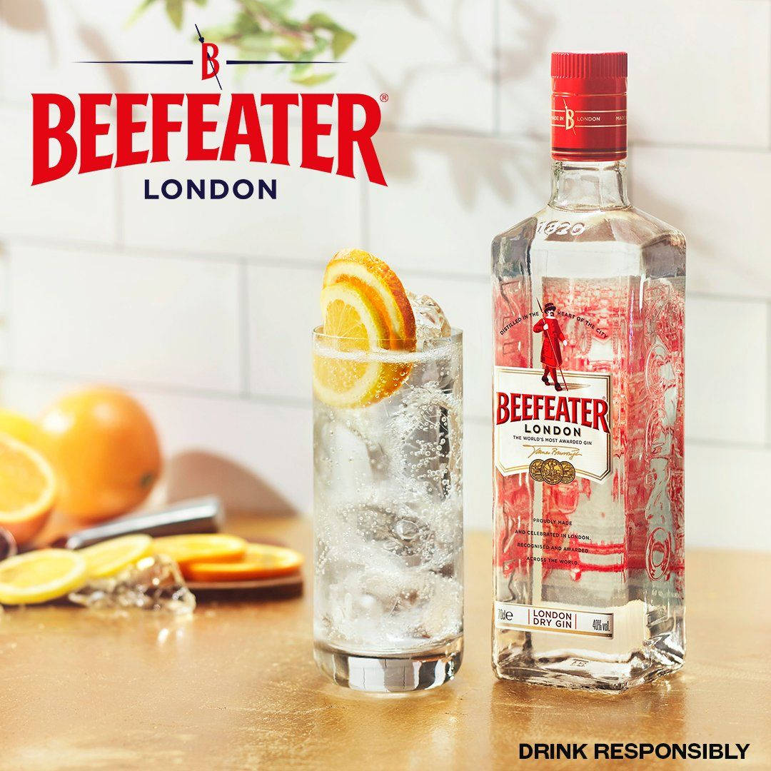 Beefeater 酒瓶與「 responsibly drink」標語 壁紙 — 一瓶必富達倫敦乾氈酒放在木製枱面上，旁邊有一杯加冰和橙片的氈酒。