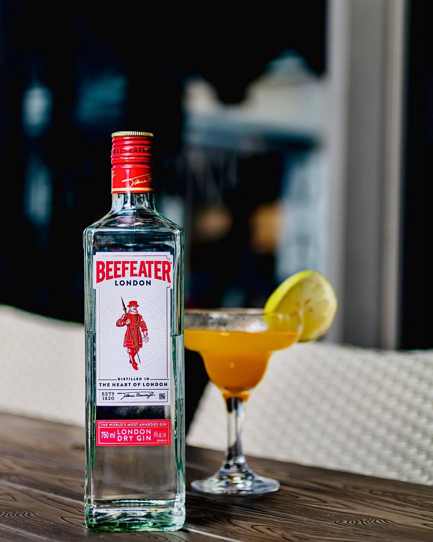 Beefeater氈酒瓶和雞尾酒在晚上的木桌上