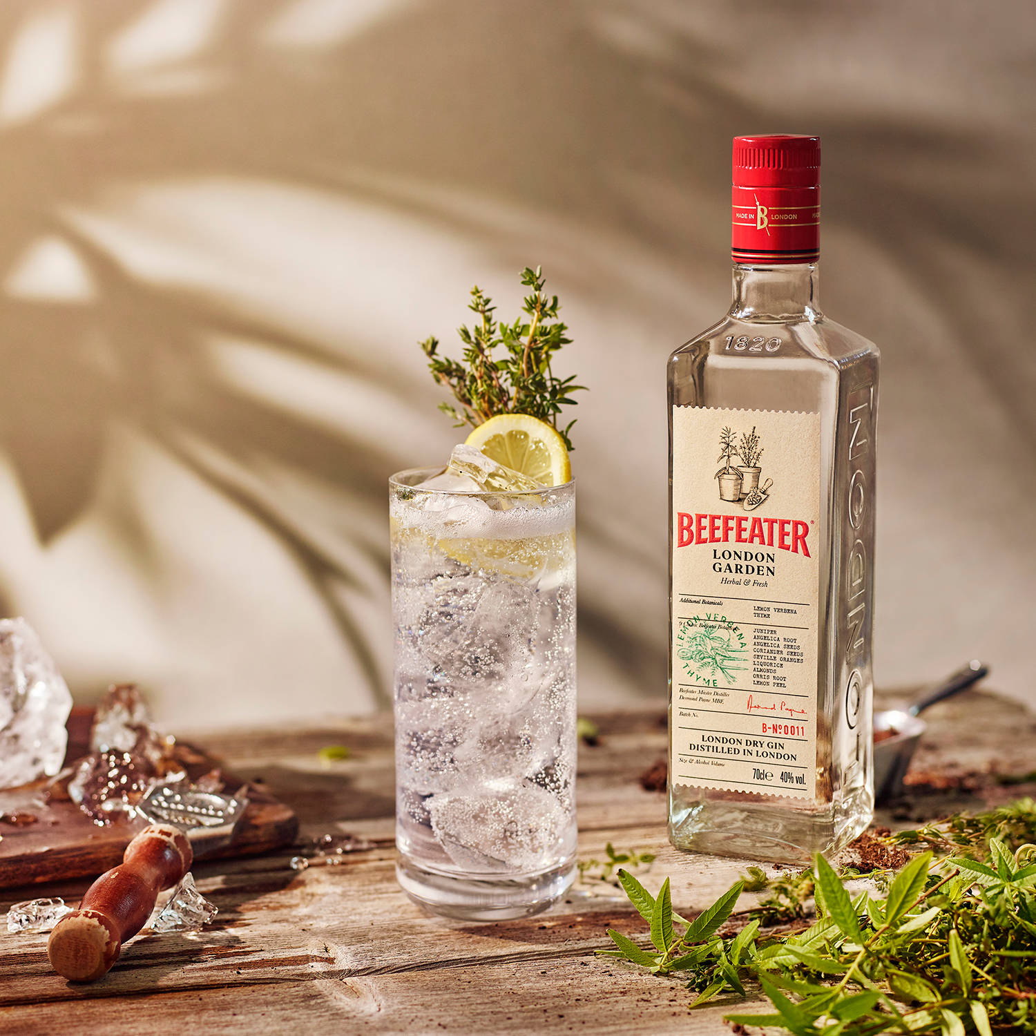 Beefeater 氈酒樽同氈酒雞尾酒配檸檬同香草喺木枱上。