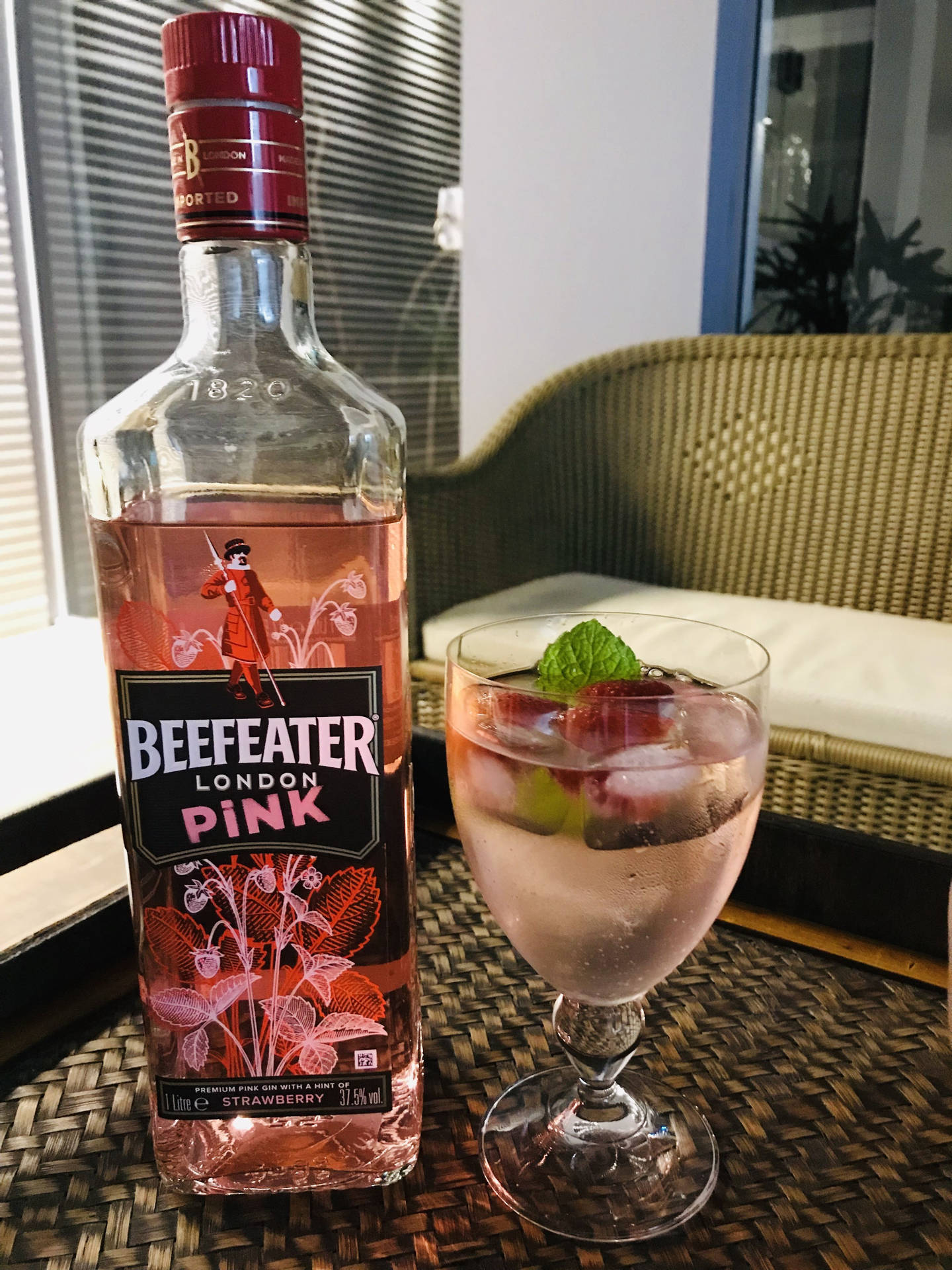 Beefeater Pink氈酒瓶和草莓薄荷雞尾酒在藤編托盤上。