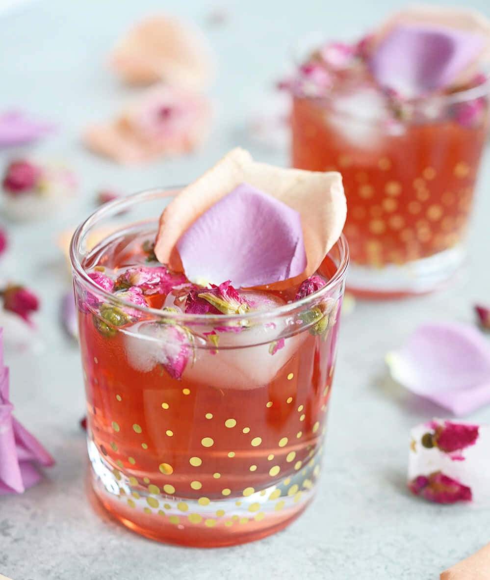 Beautiful Drink 桌布 壁紙 — 一杯充滿活力的粉紅色雞尾酒，盛載於金色圓點玻璃杯中，飾以精緻玫瑰花瓣和冰塊。