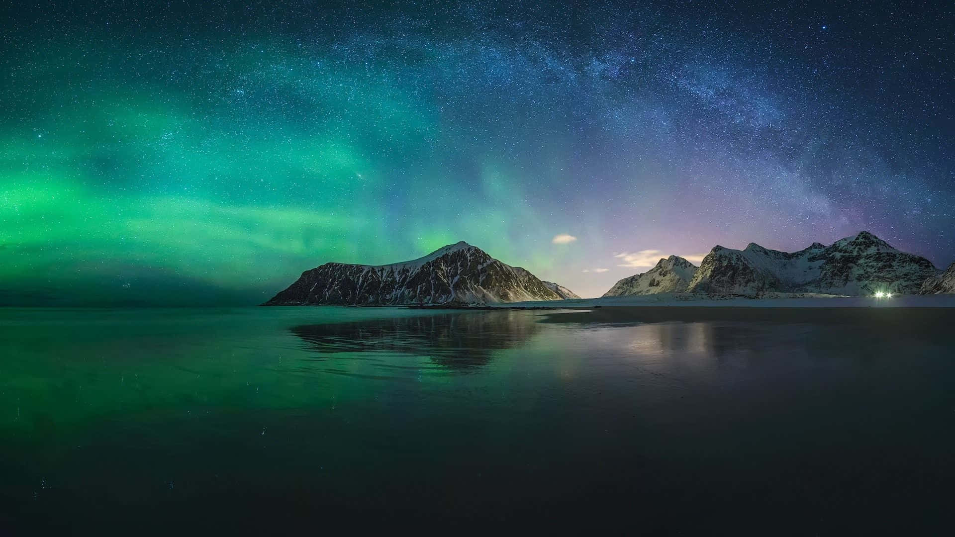 綠色北極光照亮繁星夜空下的雪山和靜水。