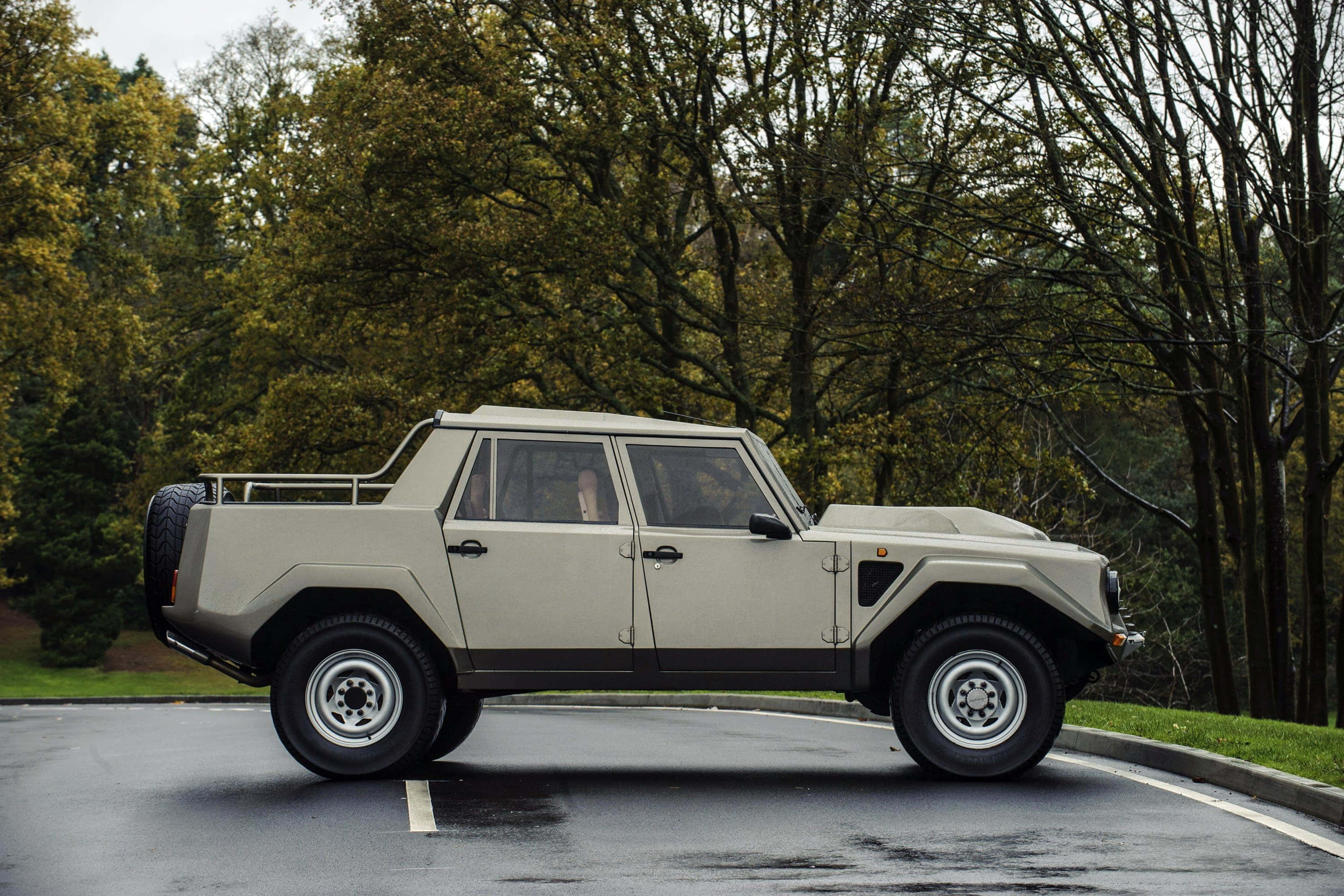 Lamborghini Lm002 桌布 壁紙 — 一輛米色林寶堅尼LM002 SUV停泊在潮濕的瀝青路上，周圍是秋天的樹木。