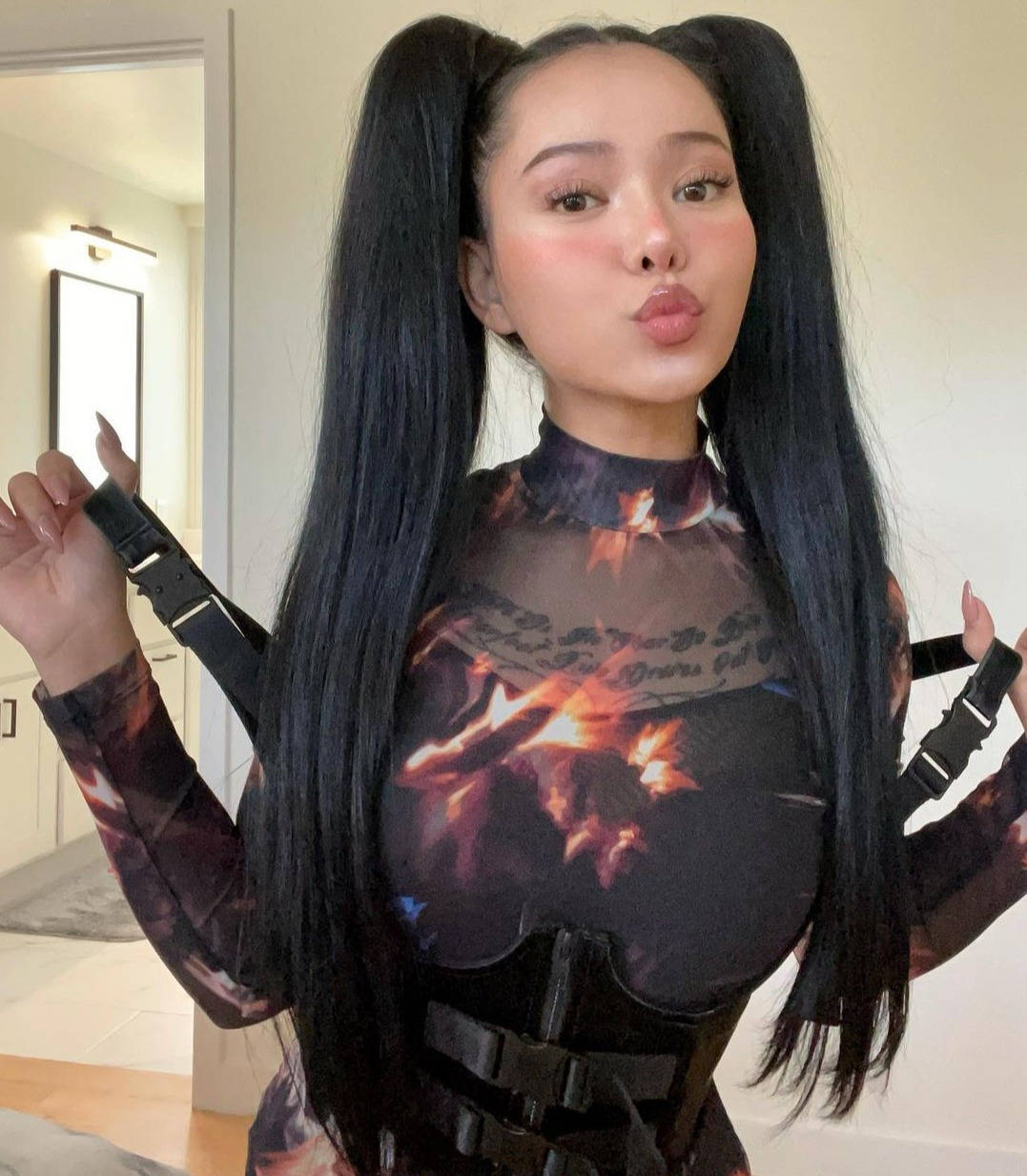 Bella Poarch 時尚黑色長袖造型 壁紙 — 一位留著黑色長辮子的女性，穿著帶有黑色背帶的火焰圖案服裝，在室內擺姿勢。