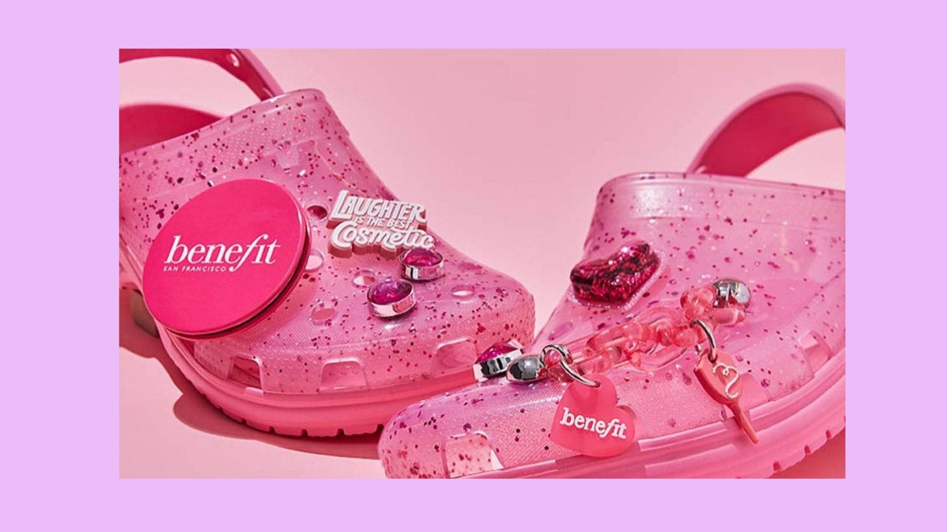Benefit聯名Crocs 壁紙 — 閃爍粉紅色閃粉木屐，飾有Benefit化妝品吊飾和心形配件，襯以柔和粉紅色背景。