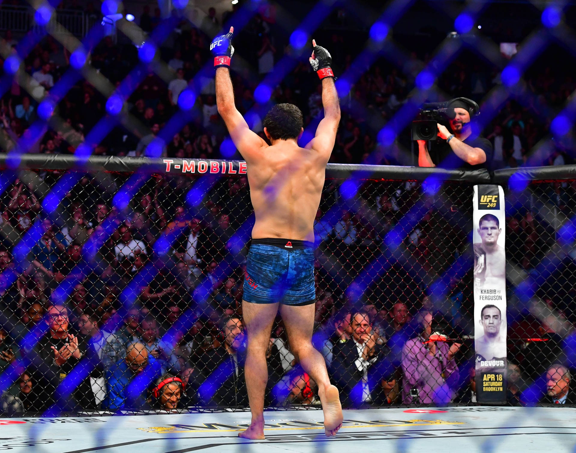 MMA拳手在八角籠中舉臂慶祝勝利。