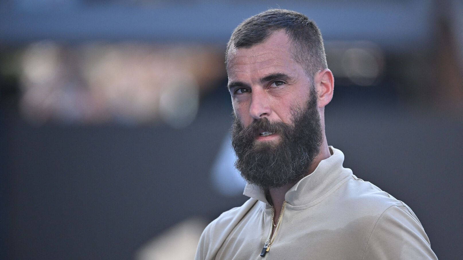 Benoit Paire 凝視遠方 壁紙 — 一位留鬍鬚的男子穿著淺色拉鍊領襯衫的特寫肖像，表情嚴肅地專注看著鏡頭外。