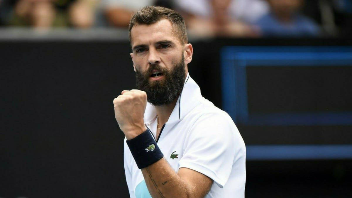 Benoit Paire 場上揮拍 壁紙 — 鬍鬚網球選手身穿白衫，在球場上握拳慶祝勝利，背景有模糊的觀眾。