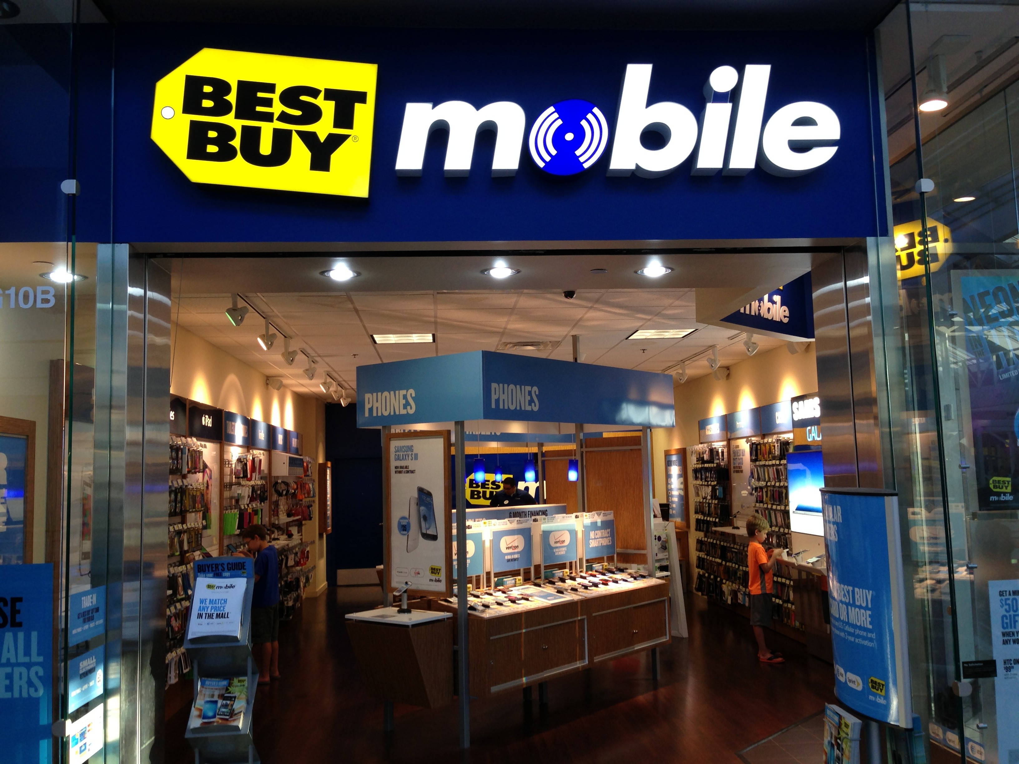 Best Buy移動店鋪 壁紙 — 光線充足的Best Buy Mobile店舖正面，設有玻璃門和內部手機展示。