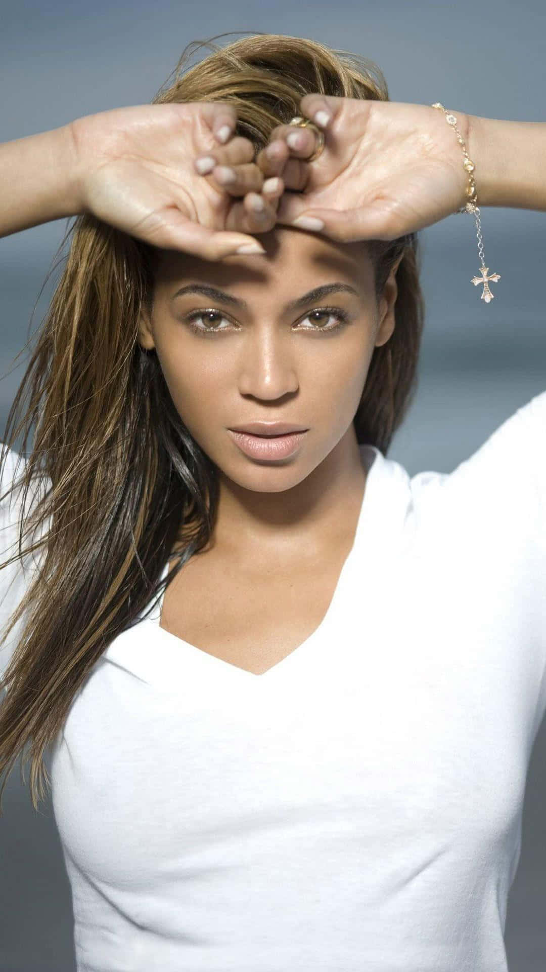 Beyoncé 桌布 壁紙 — Beyoncé 喺柔和灰色背景前用手托住臉頰，身穿白色V領恤衫擺甫士。
