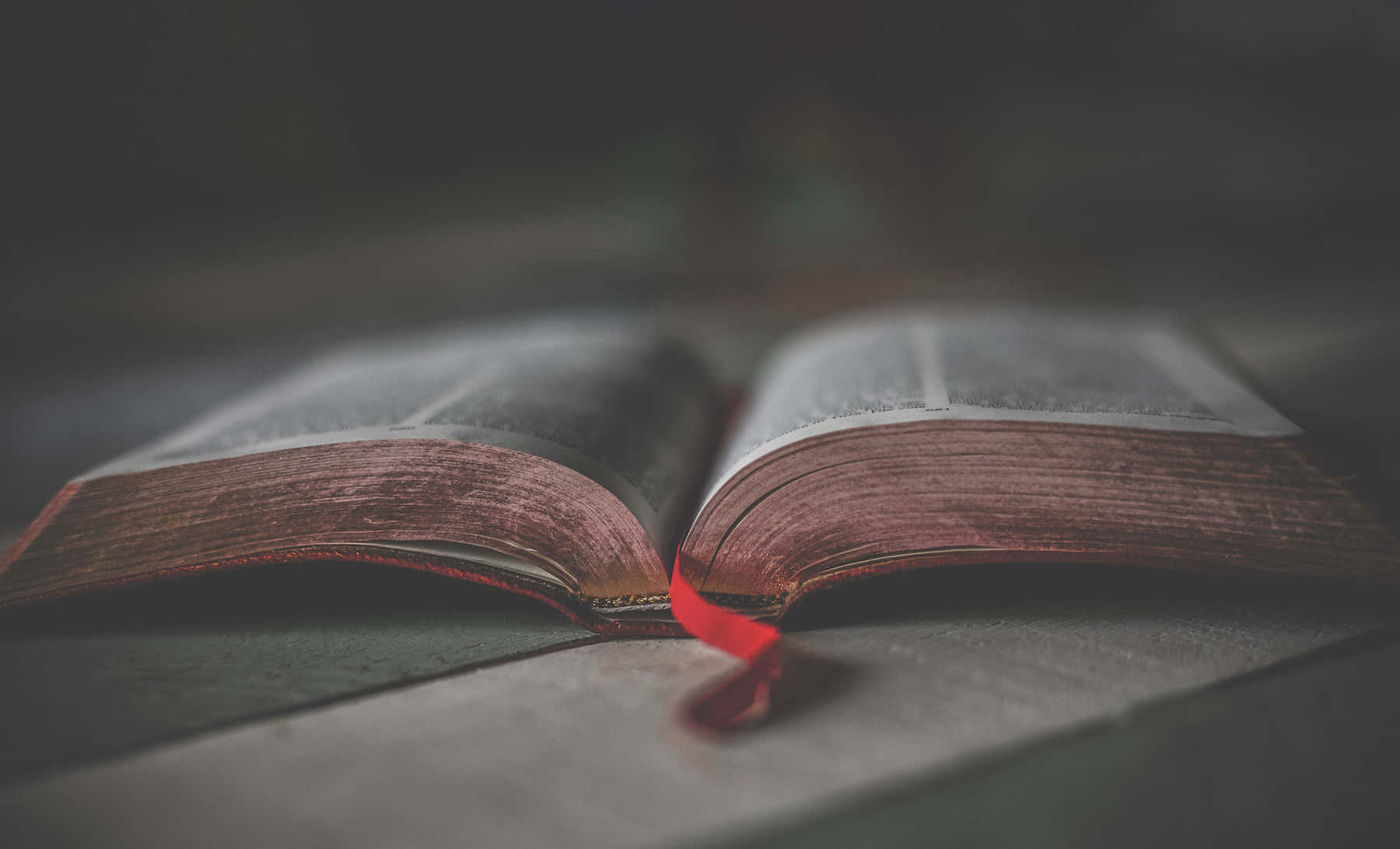 一本打開的書，帶有紅色書籤，放在木質表面上。