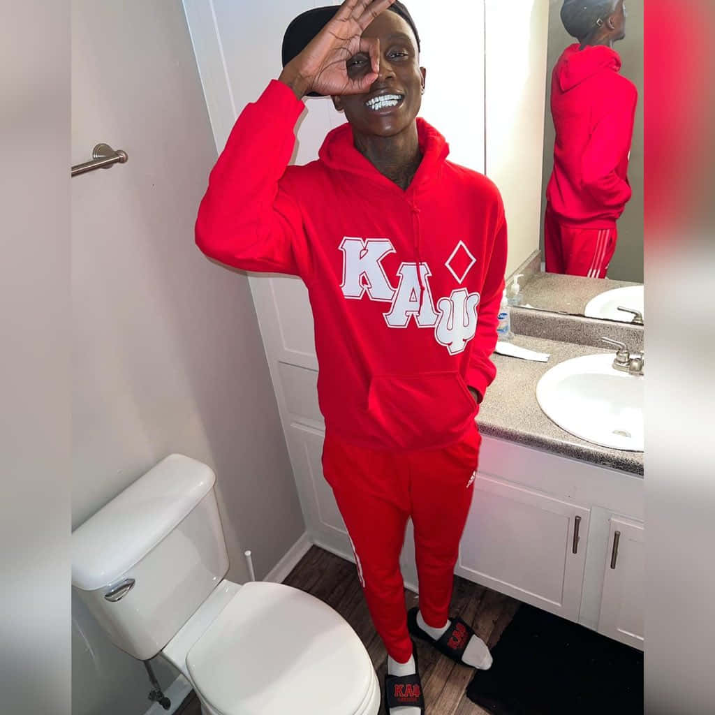 身穿紅色Kappa運動服的男人在浴室鏡中微笑並做手勢。