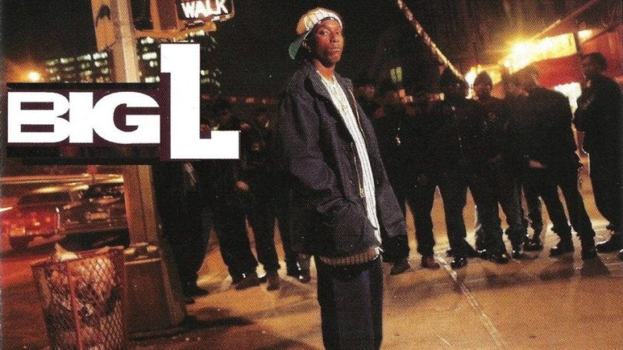 Big L《Lifestylez ov da Poor & Dangerous》專輯封面 壁紙 — 一個戴著帽子和穿著外套的男人在夜晚濕漉漉的城市街道上，在閃爍的路燈下自信地站立，帶有 'BIG L' 標誌覆蓋層。