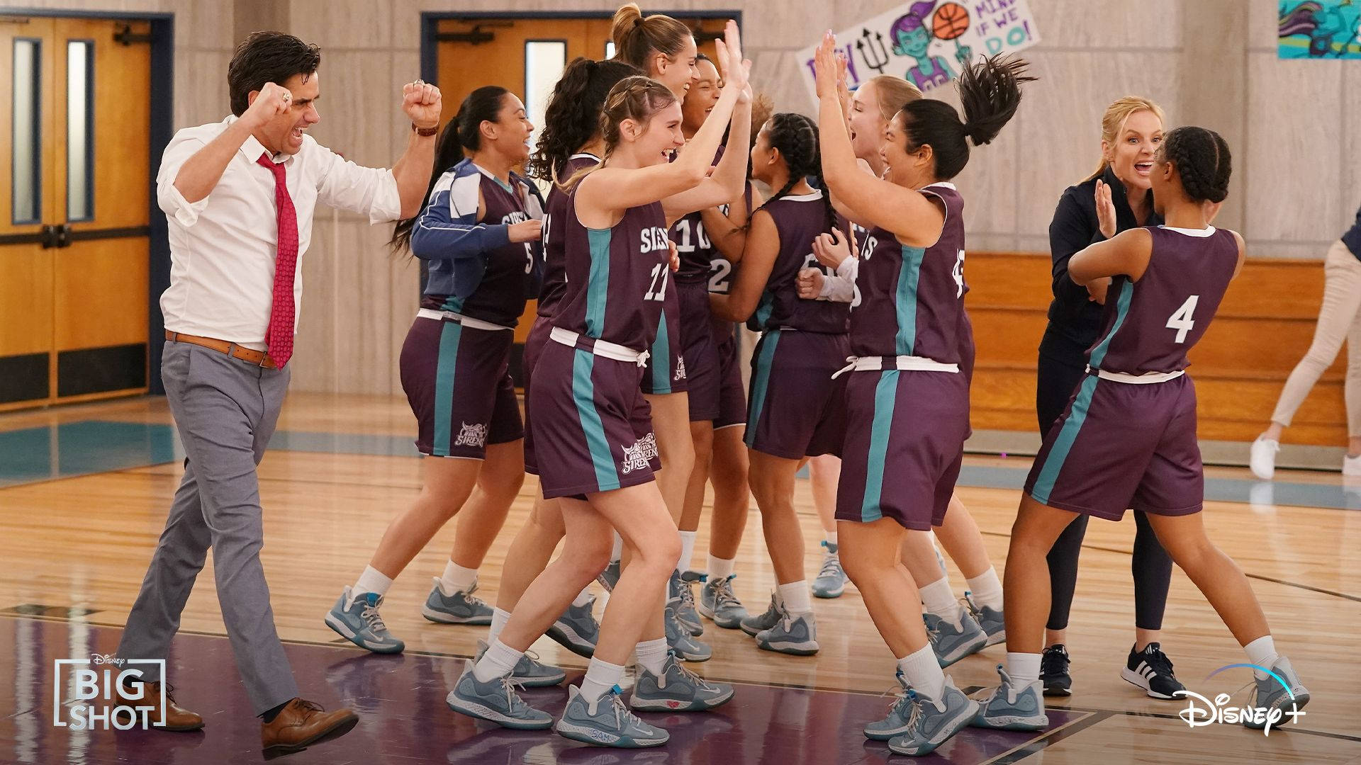 女子籃球隊在比賽獲勝後與教練擊掌歡呼。