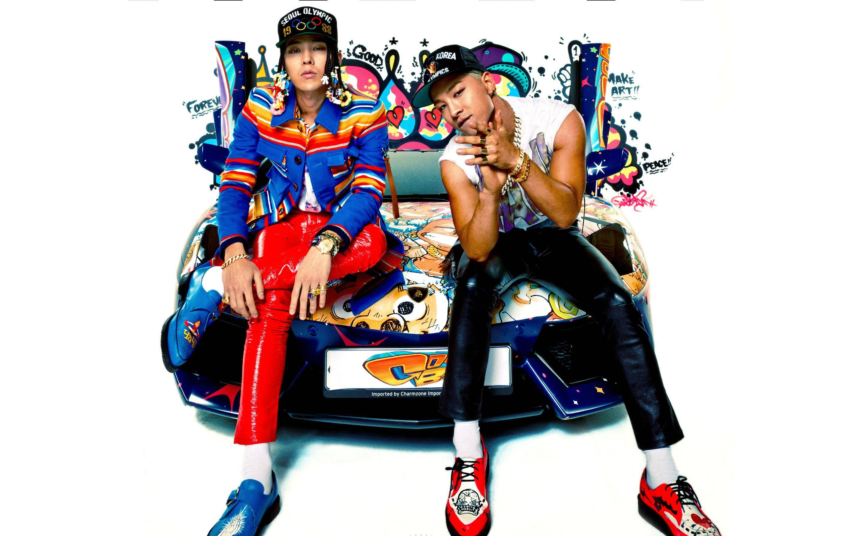 Bigbang G Dragon 與 Sol 街頭塗鴉 壁紙 — 兩位穿著時尚的男士自信地在一輛塗滿塗鴉的汽車上擺姿勢，背景是純白色。