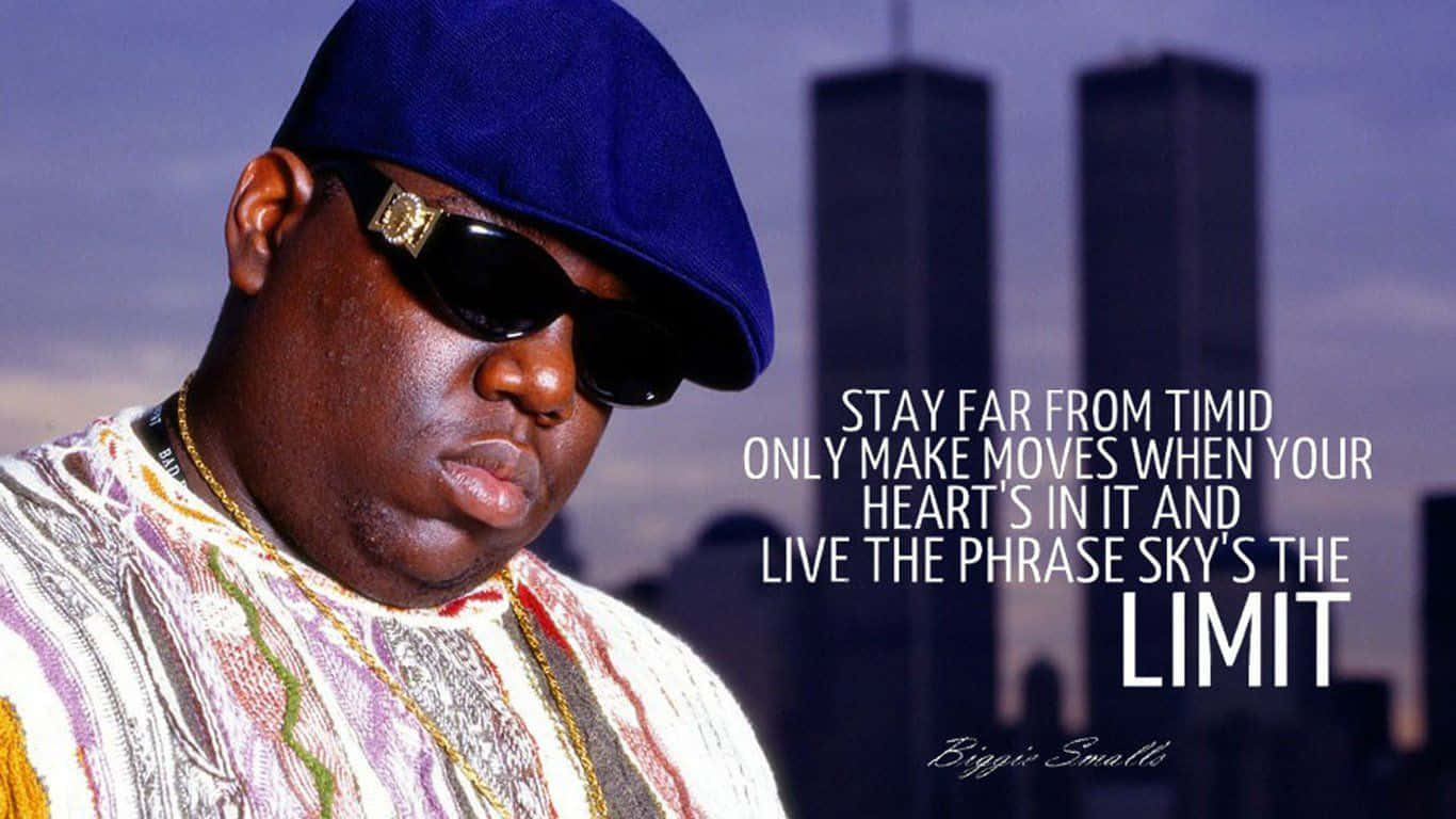 致敬 Biggie Smalls：嘻哈界的傳奇人物 壁紙 — Biggie Smalls 戴著藍色帽和太陽眼鏡，自信地在雙子塔前擺姿勢，並帶有勵志文字疊加。