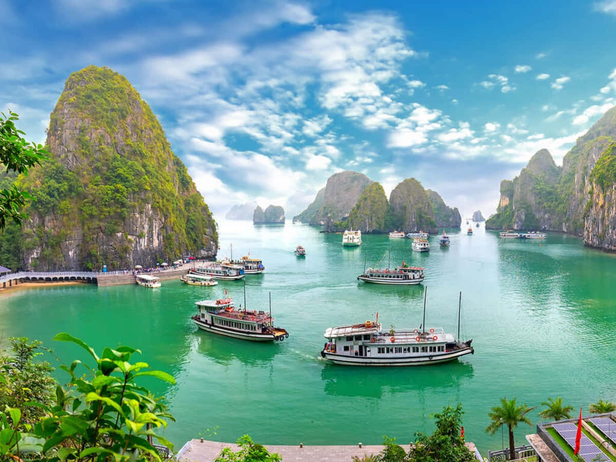 船隻在下龍灣高聳的石灰岩喀斯特地貌間的碧綠海水中航行。