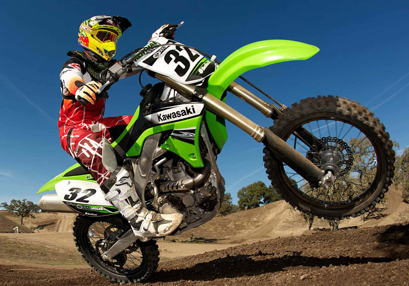 越野摩托車手在藍天下於泥地賽道上騎著綠色 Kawasaki 摩托車轉彎