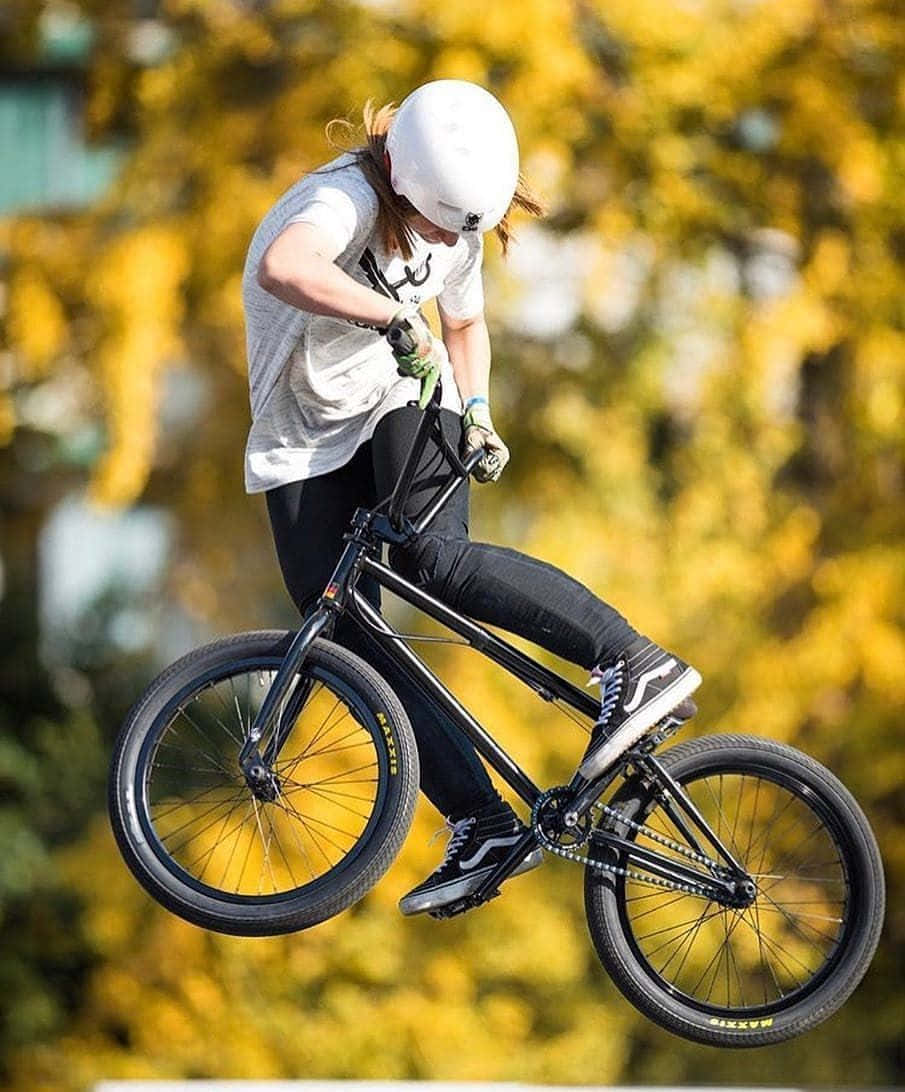 BMX車手在空中跳躍，背景是金色的秋葉。