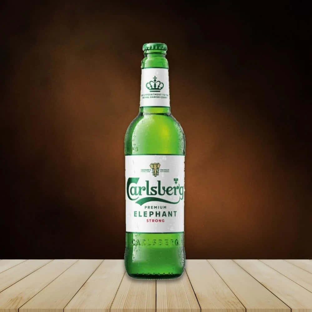  壁紙 — 一支冰凍的綠色Carlsberg Premium Elephant Strong啤酒瓶在淺色木質表面上閃爍著冷凝水珠，背景是溫暖的棕色漸變色。