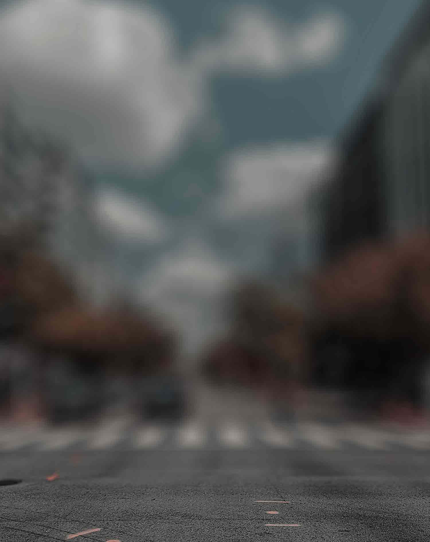 模糊的城市街道景觀，有斑馬線和建築物，天空多雲。